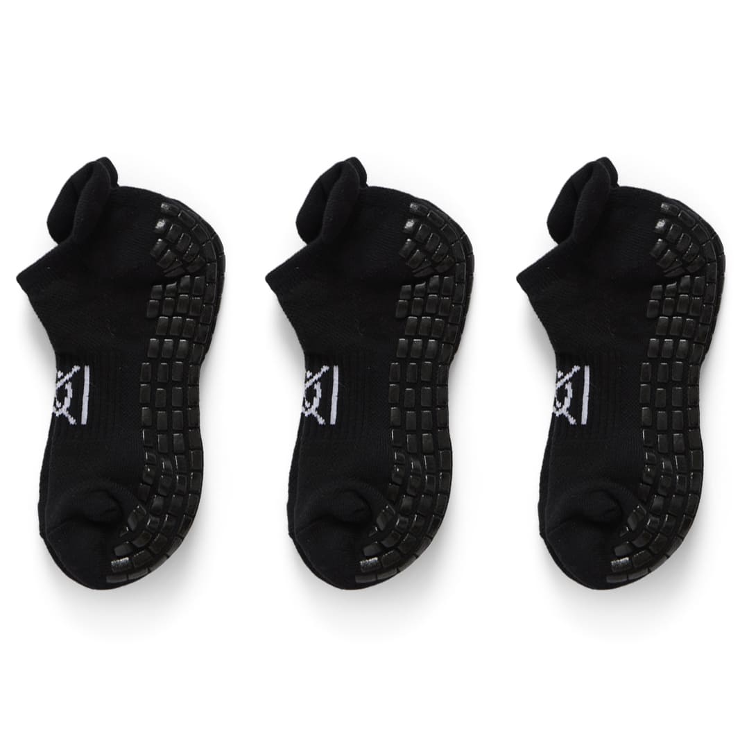 Three pairs of black golf socks with textured soles on a white background
