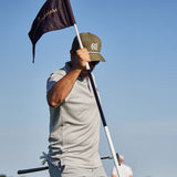 Golfer holding a flagstick with a clear blue sky in the background