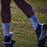 Person wearing white socks with 'Koi Golf' branding on a grassy field.