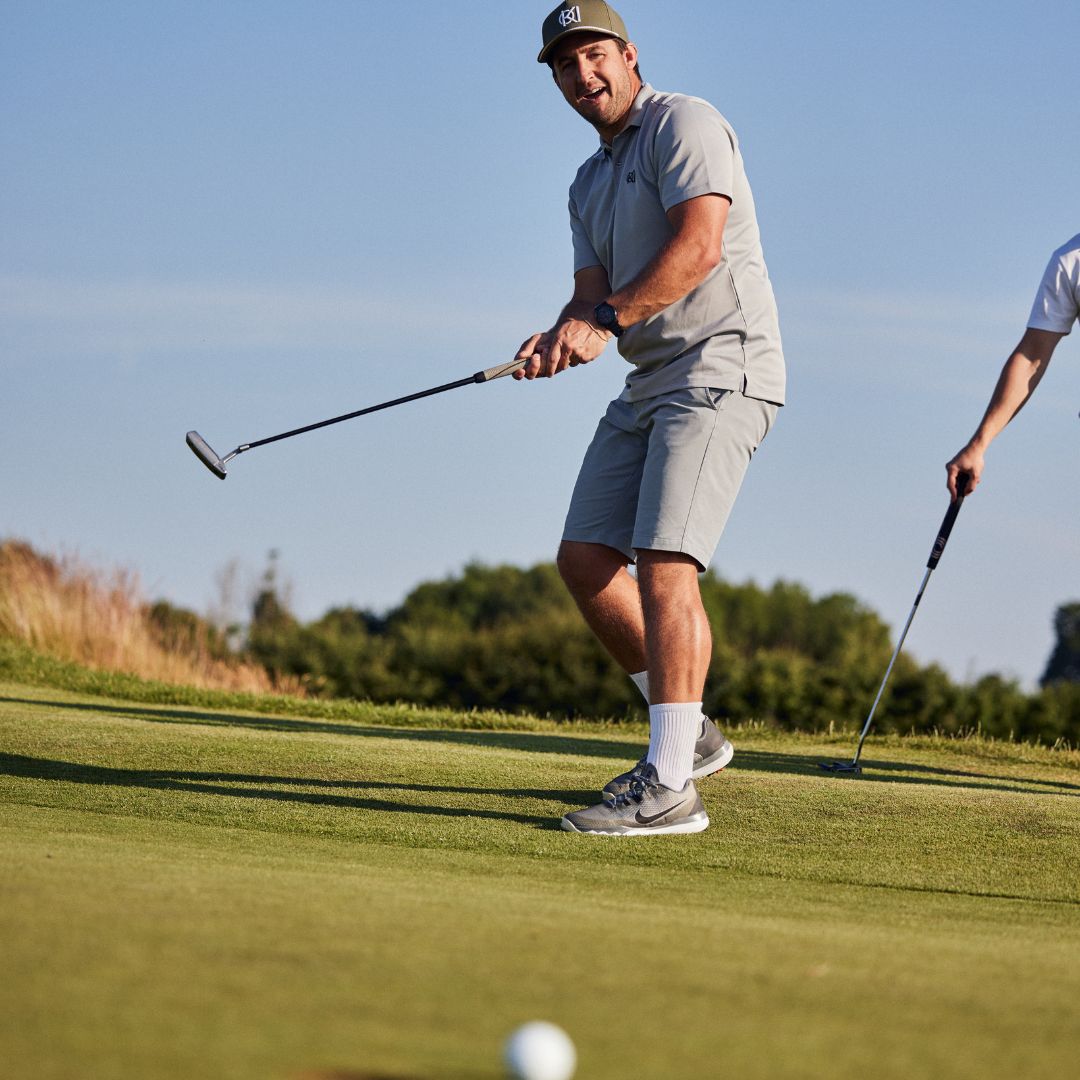 Man playing golf on a green course with clear sky