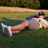 Golfer lying on grass wearing a cap and socks with brand logos