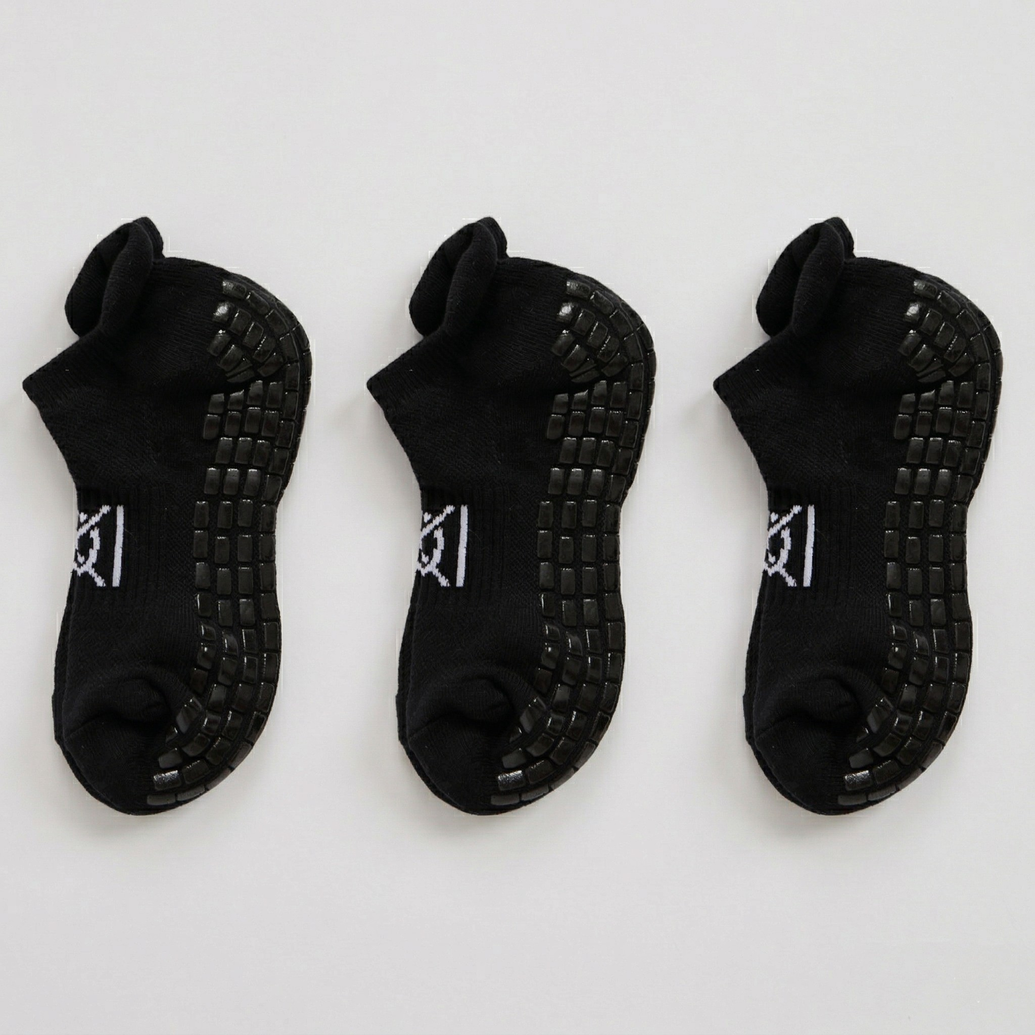 Three pairs of black socks with textured soles on a white background