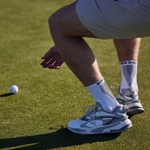 Person on a golf course with a golf ball and socks visible