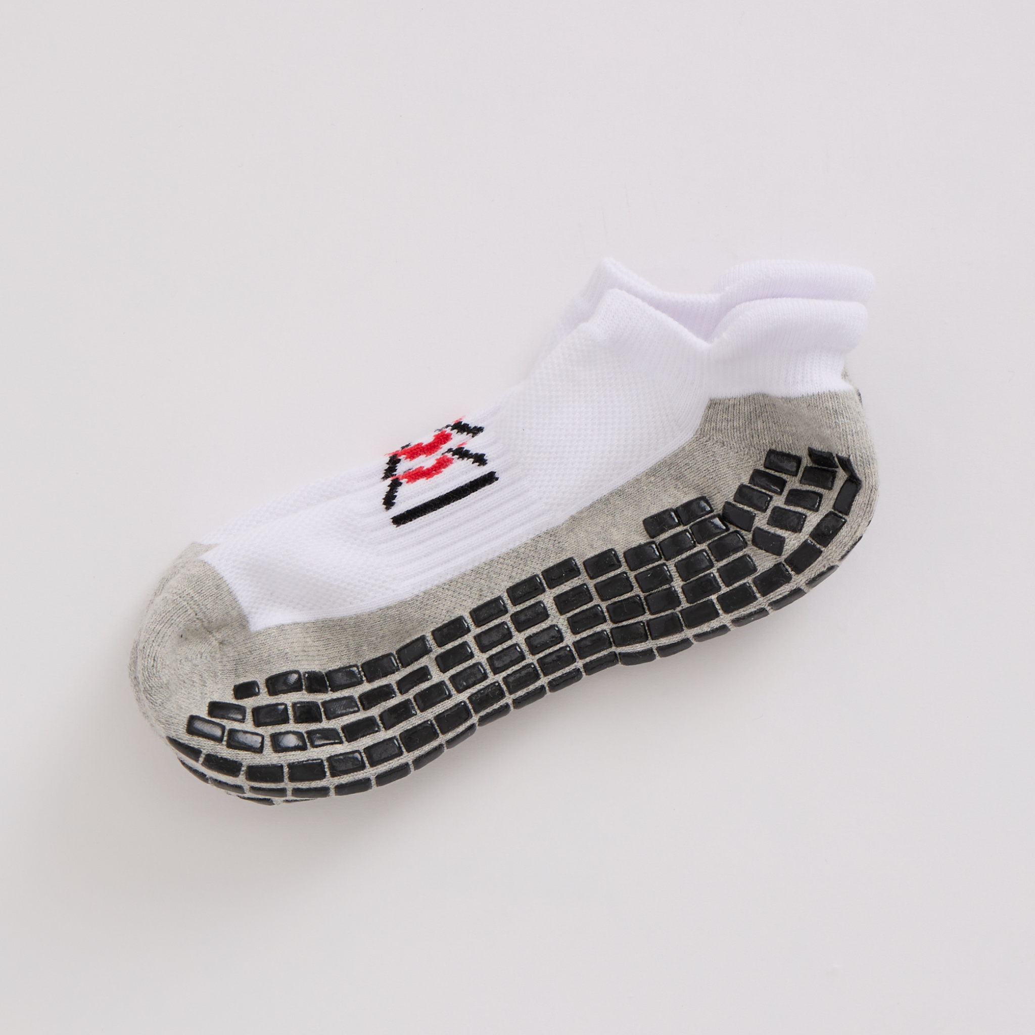 White ankle sock with black textured sole on a light gray background