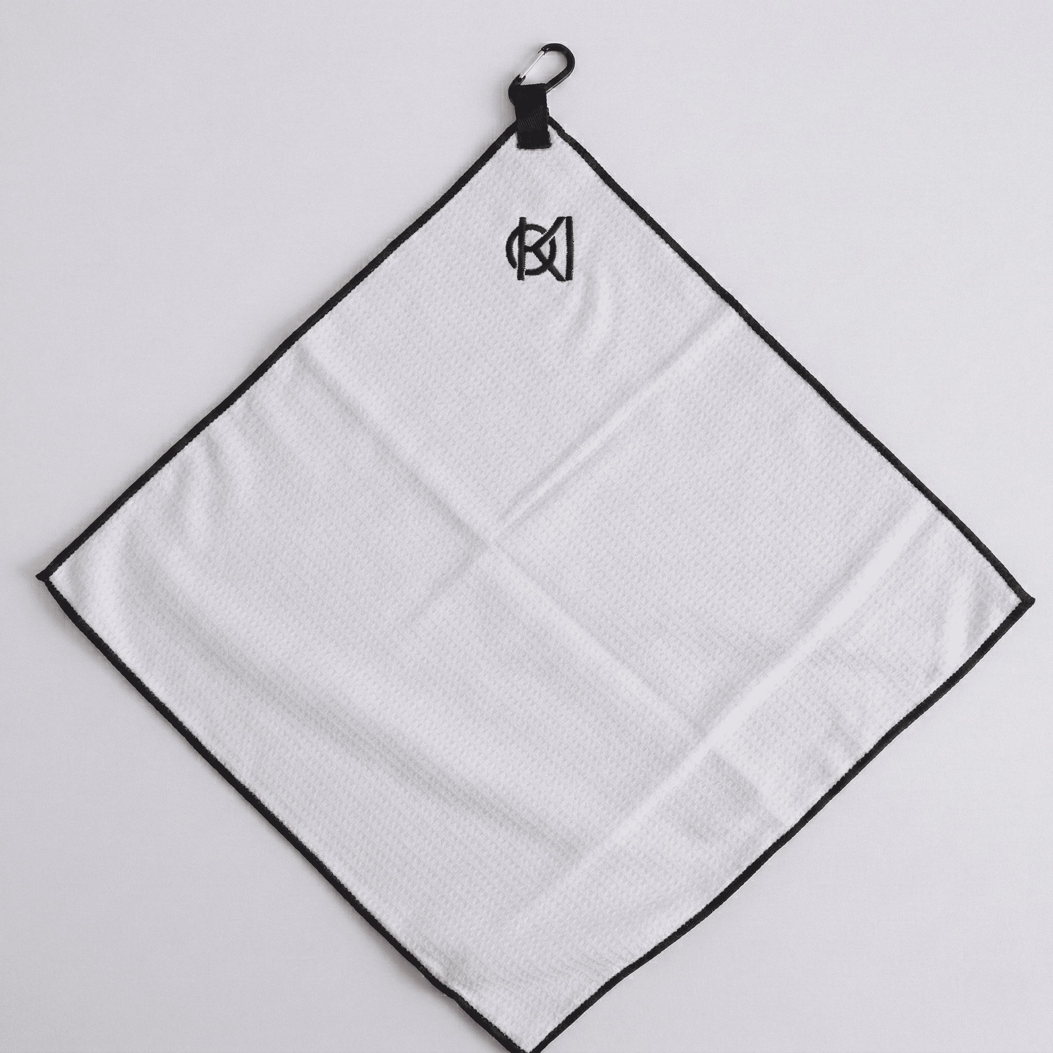 White towel with black border hanging on a hook against a light gray background
