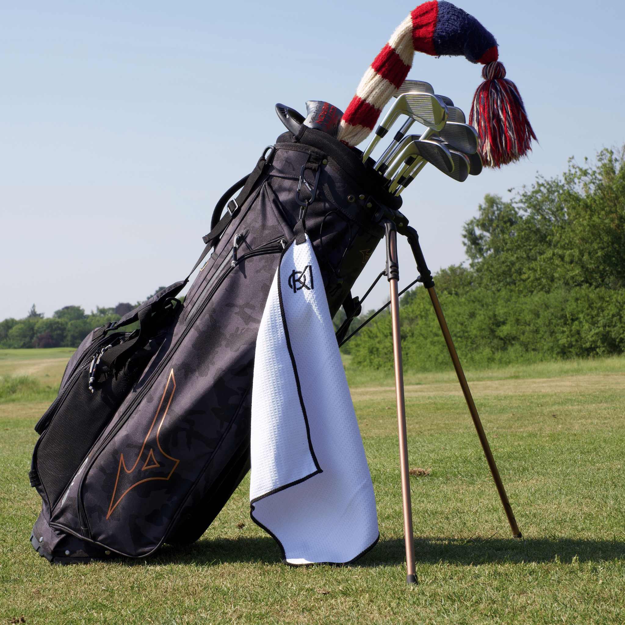 Golf bag with golf clubs and a golf towel item on a grassy field