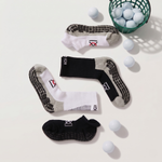 Four pairs of socks with different designs on a light surface, surrounded by white golfballs.