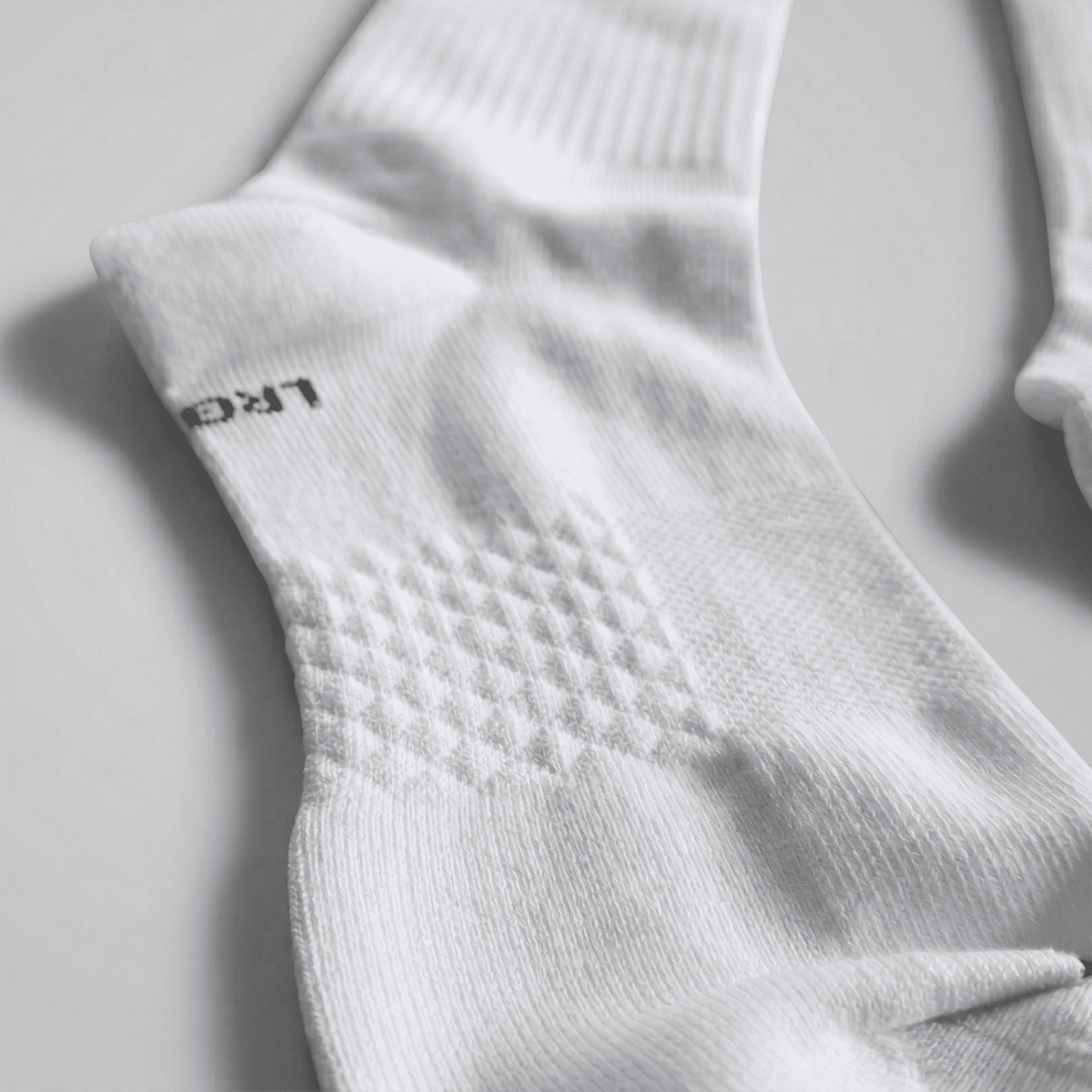 Close-up of a white sock with 'LARGE' text on a light gray background